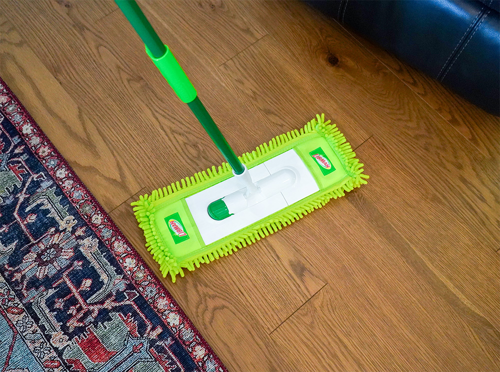 Dust mop being used to clean wood floor
