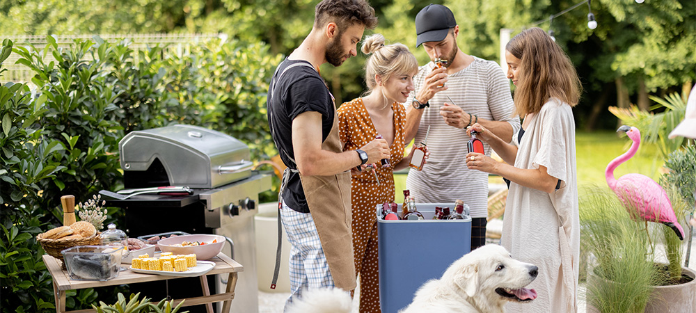 Four people standing around a cooler outside at a barbeque