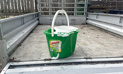 Green bucket filled with soapy water sitting in a truck bed