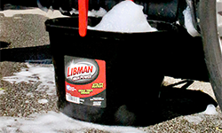 Black plastic bucket ful of soapy water outdoors on pavement