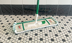 Flat mop being used to clean bathroom floor