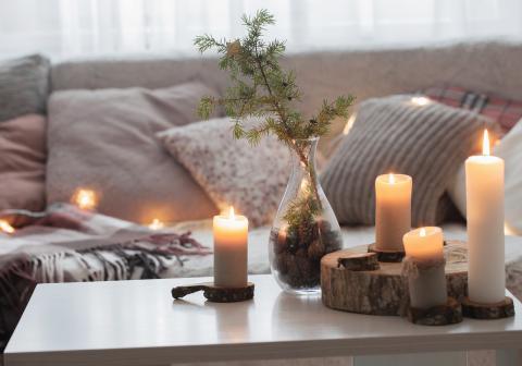 Cozy living room with lit candles, and a pinetree branch in a vase