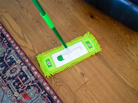 Dust mop being used to clean wood floor