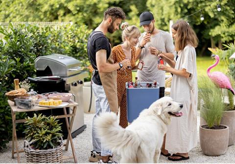 Four people standing around a cooler outdoors at a barbeque